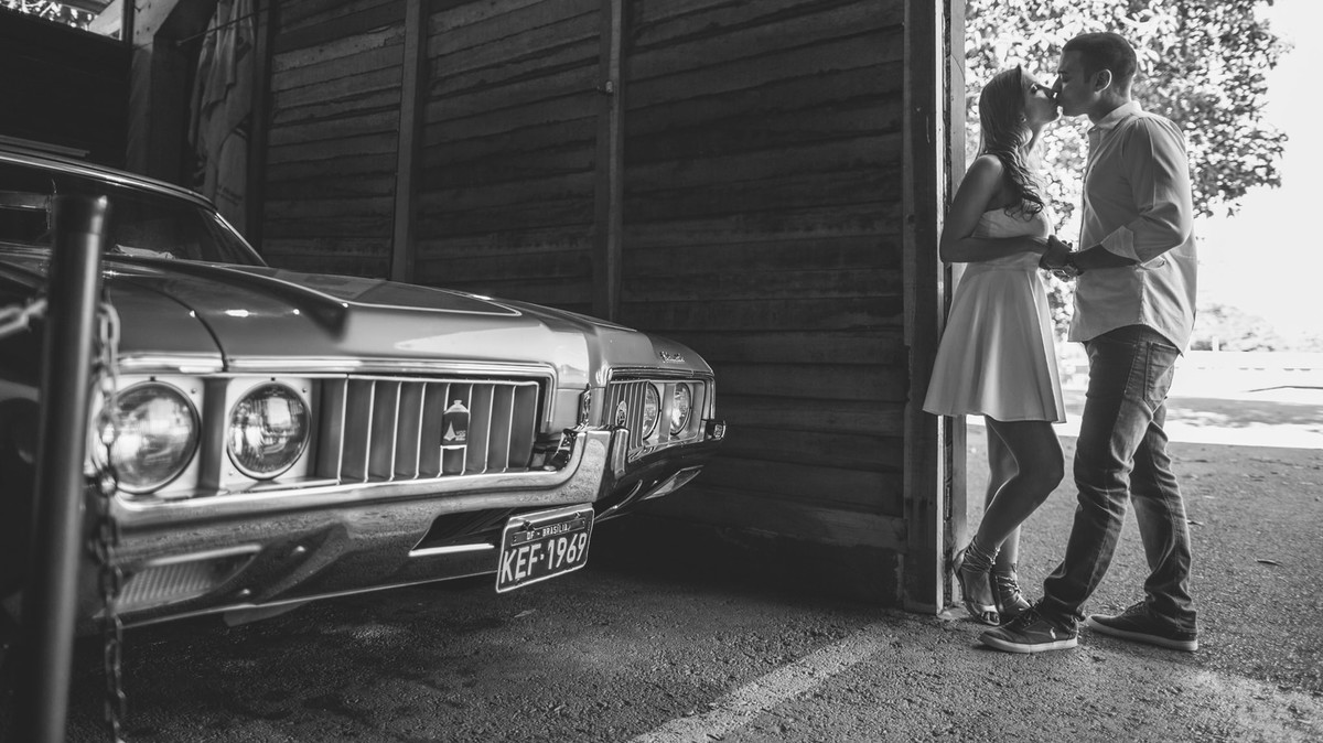 Casal se beijando em uma garagem de carros antigos. Casal abraçado se olhando. Foto feita pelo fotógrafo de casamento Rafael Ohana em Brasília-DF