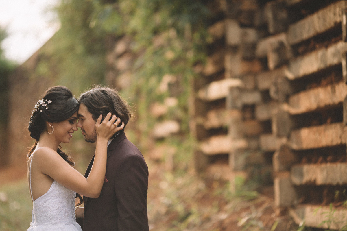 Casal se amando perto de um grande muro cheio de folhas. Fotografado pelo fotógrafo de casamento Rafael Ohana em Brasília-DF
