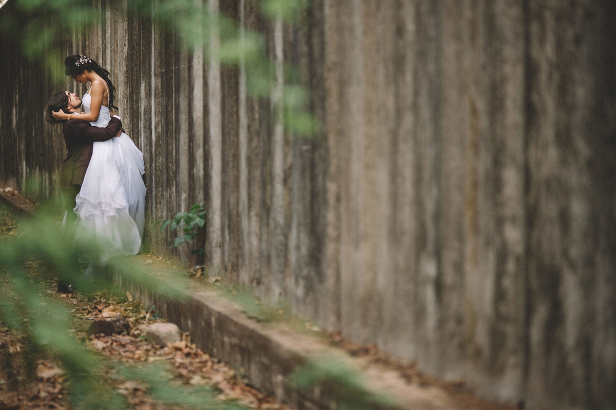 Noivos se beijando perto de um grande muro de concreto. Fotografado pelo fotógrafo de casamento Rafael Ohana em Brasília-DF