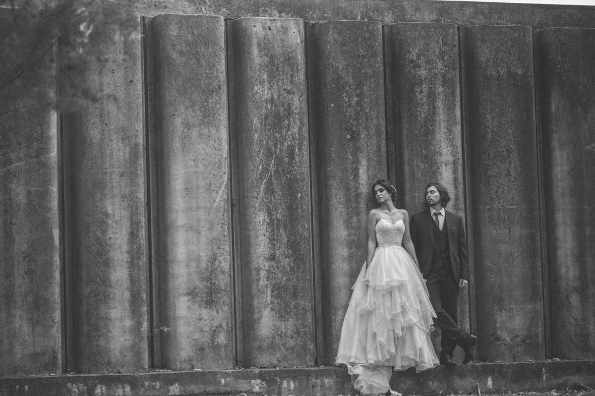 Noivos encostados em um grande muro de concreto. Fotografado pelo fotógrafo de casamento Rafael Ohana em Brasília-DF