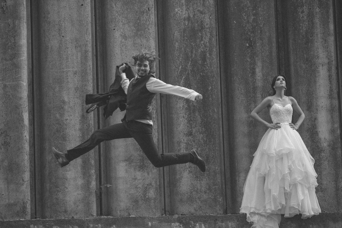 Noivo pulando segurando paletó enquanto noiva olha para cima. Fotografado pelo fotógrafo de casamento Rafael Ohana em Brasília-DF