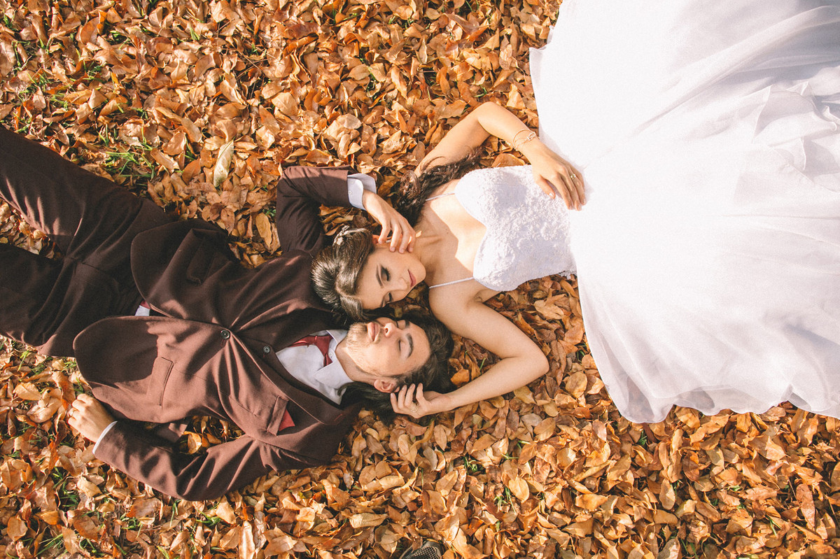 Noivos deitados no chão cheio de folhas. Fotografado pelo fotógrafo de casamento Rafael Ohana em Brasília-DF