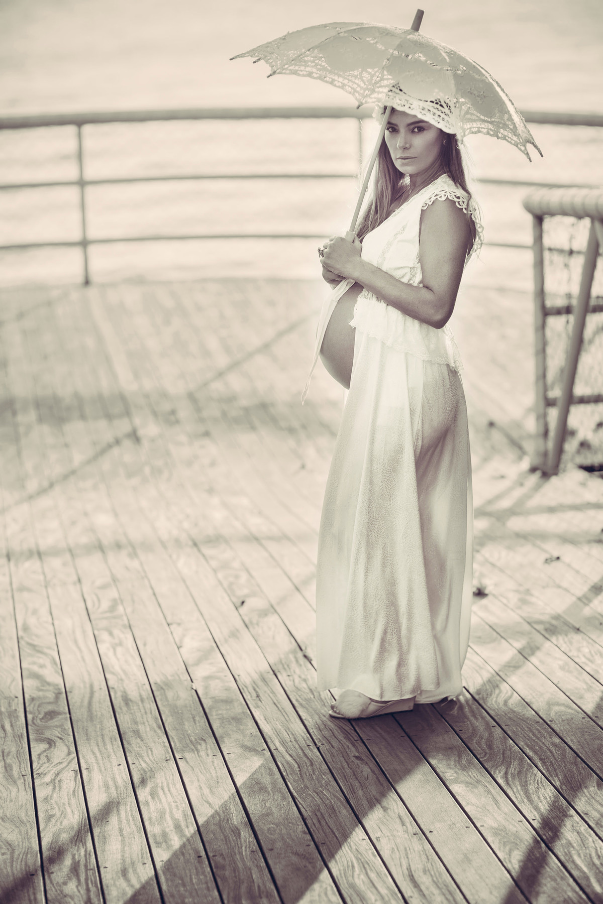 Grávida usando vestido branco e segurando sombrinha branca. Fotografado pelo fotógrafo de gestantes Rafael Ohana em Manaus-AM