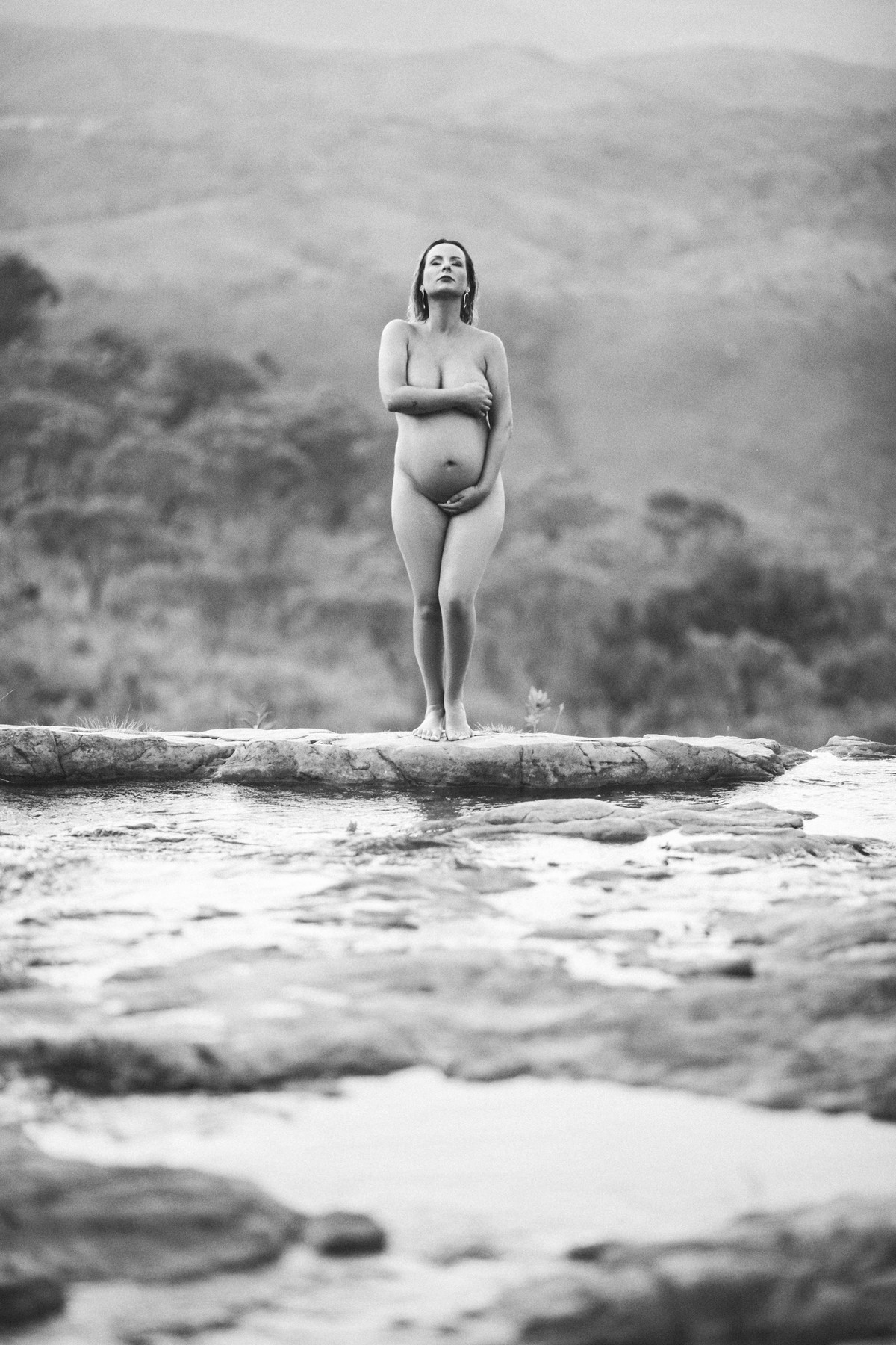 Grávida nua posando nas pedras de um rio. Clicado pelo fotógrafo de gestantes Rafael Ohana em Brasília-DF