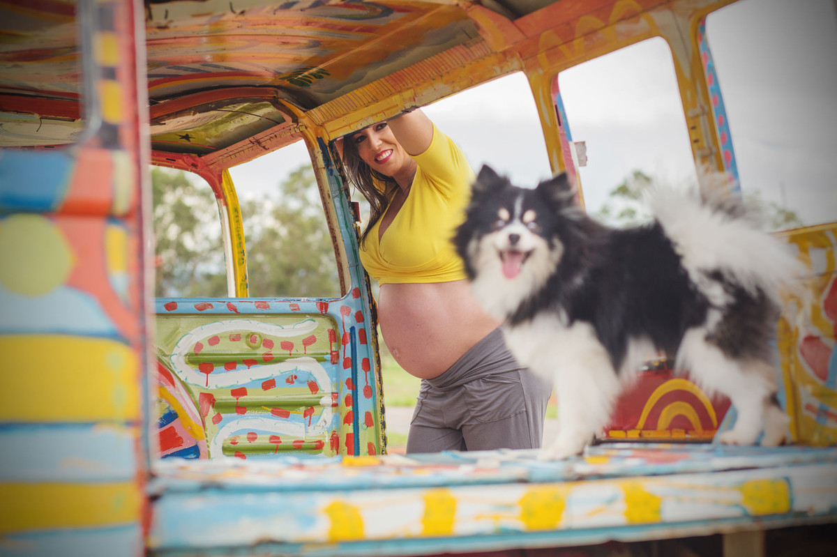 Grávida encostada em carcaça de kombi junto com seu cachorro. fotografia feita pelo fotógrafo de grávidas Rafael Ohana em Brasília