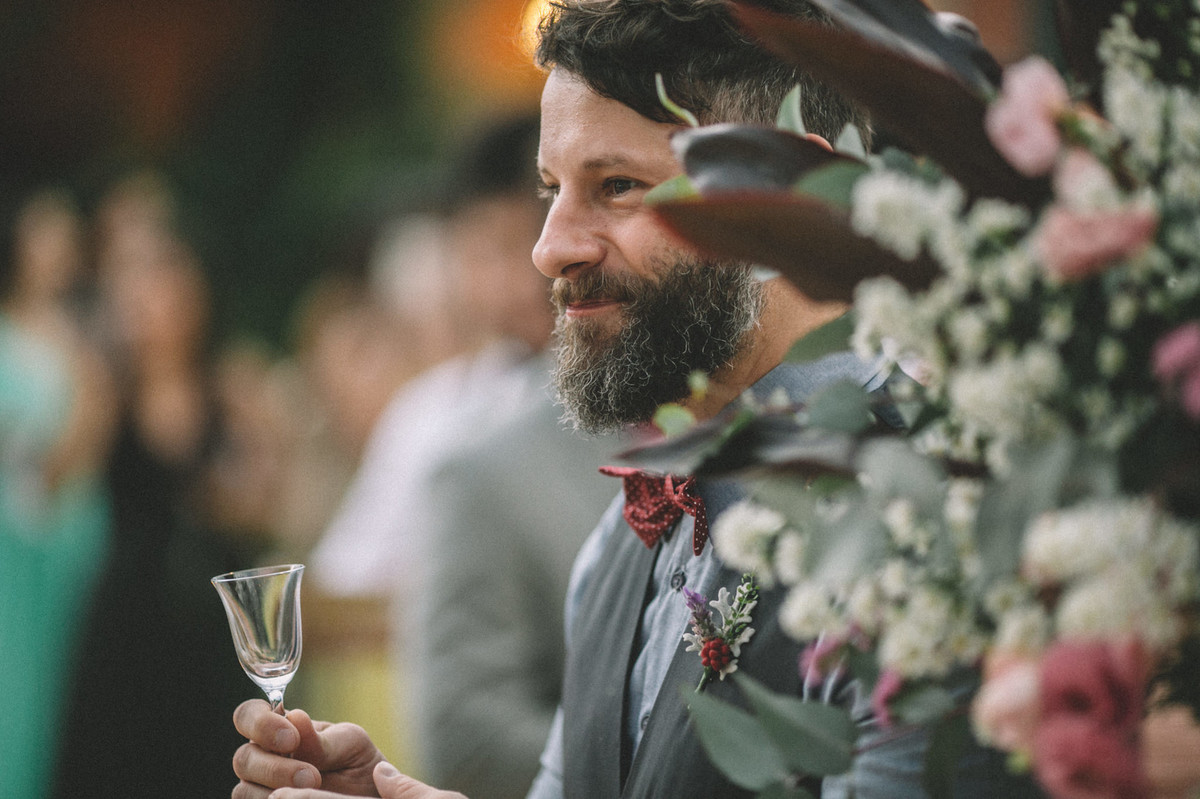 Convidado de casamento sorrindo com taça na mão no Villa Giardini em Brasília-DF