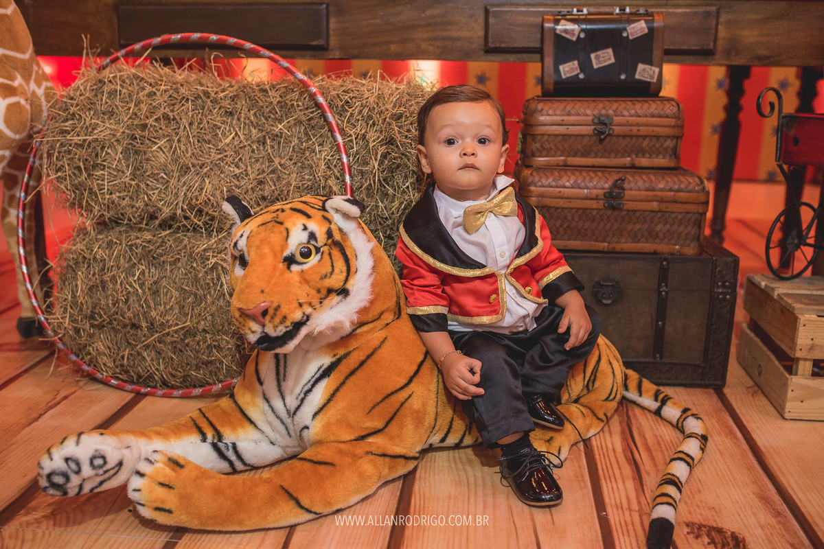 Felipe sentado no tigre no aniversário com o tema circo