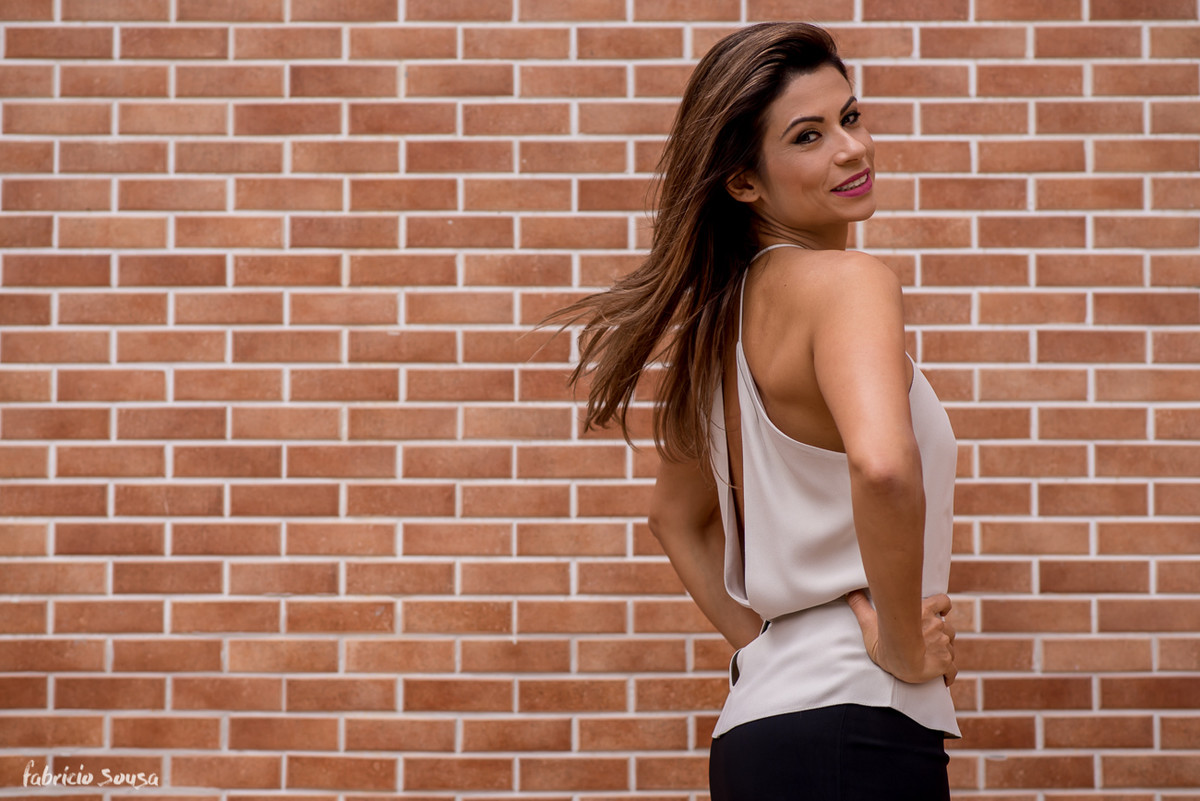 a linda Karina Peloi posa para foto em muro de tijolinhos