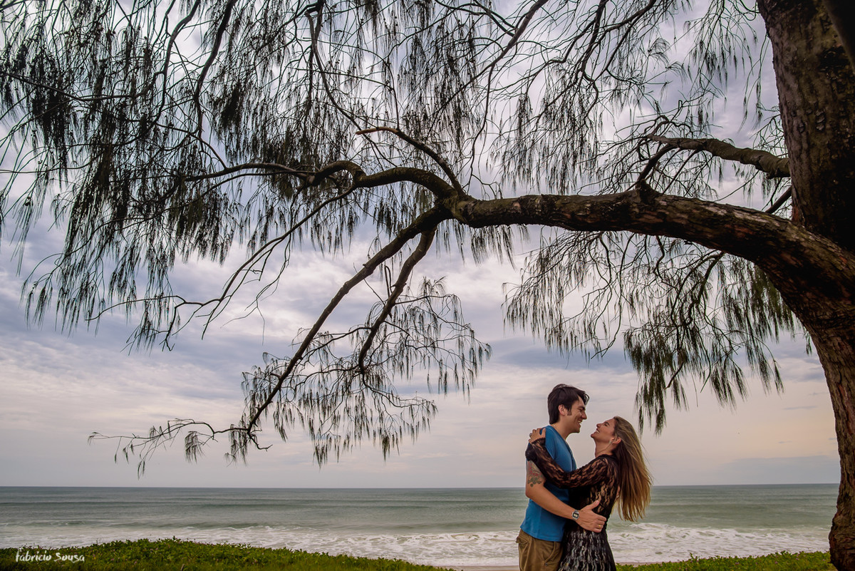 noivos sorrindo e quase se beijando embaixo da árvore na beira da praia em Florianópolis