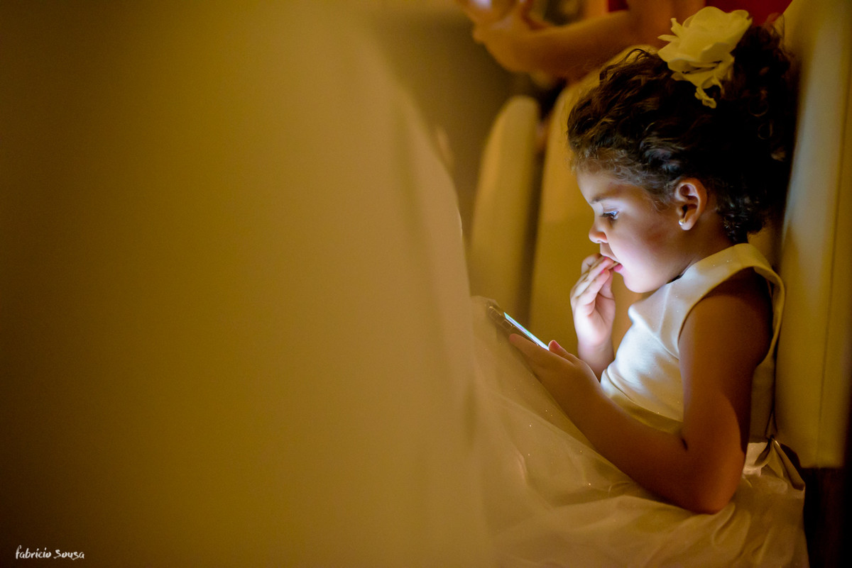 daminha brincando no celular e comendo bolacha durante a festa de casamento