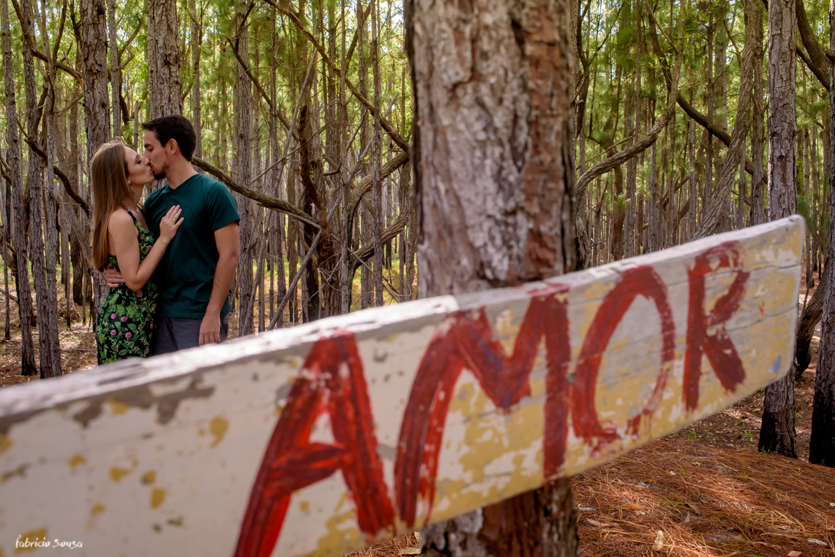 casal se beijando com placa escrito amor no bosque com luz dourada - ensaio prewedding