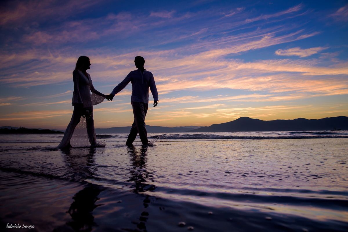 silhueta do casal caminhando na praia em um belo final de tarde - por do sol colorido