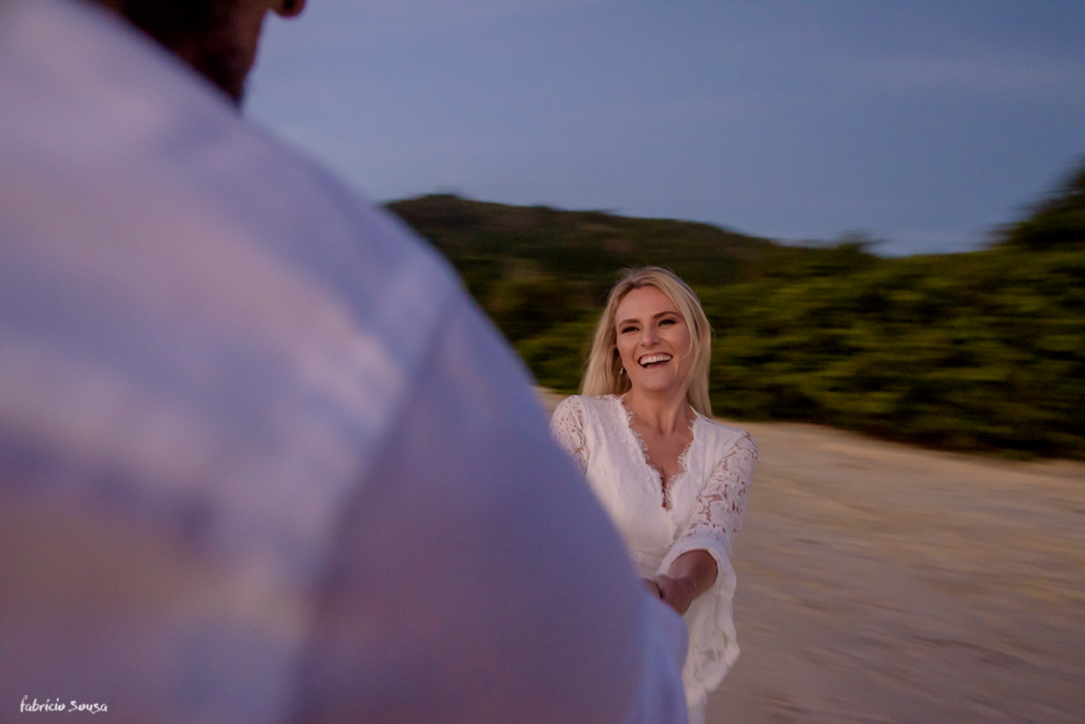 noivos brincando na praia durante sessão de fotos de casal