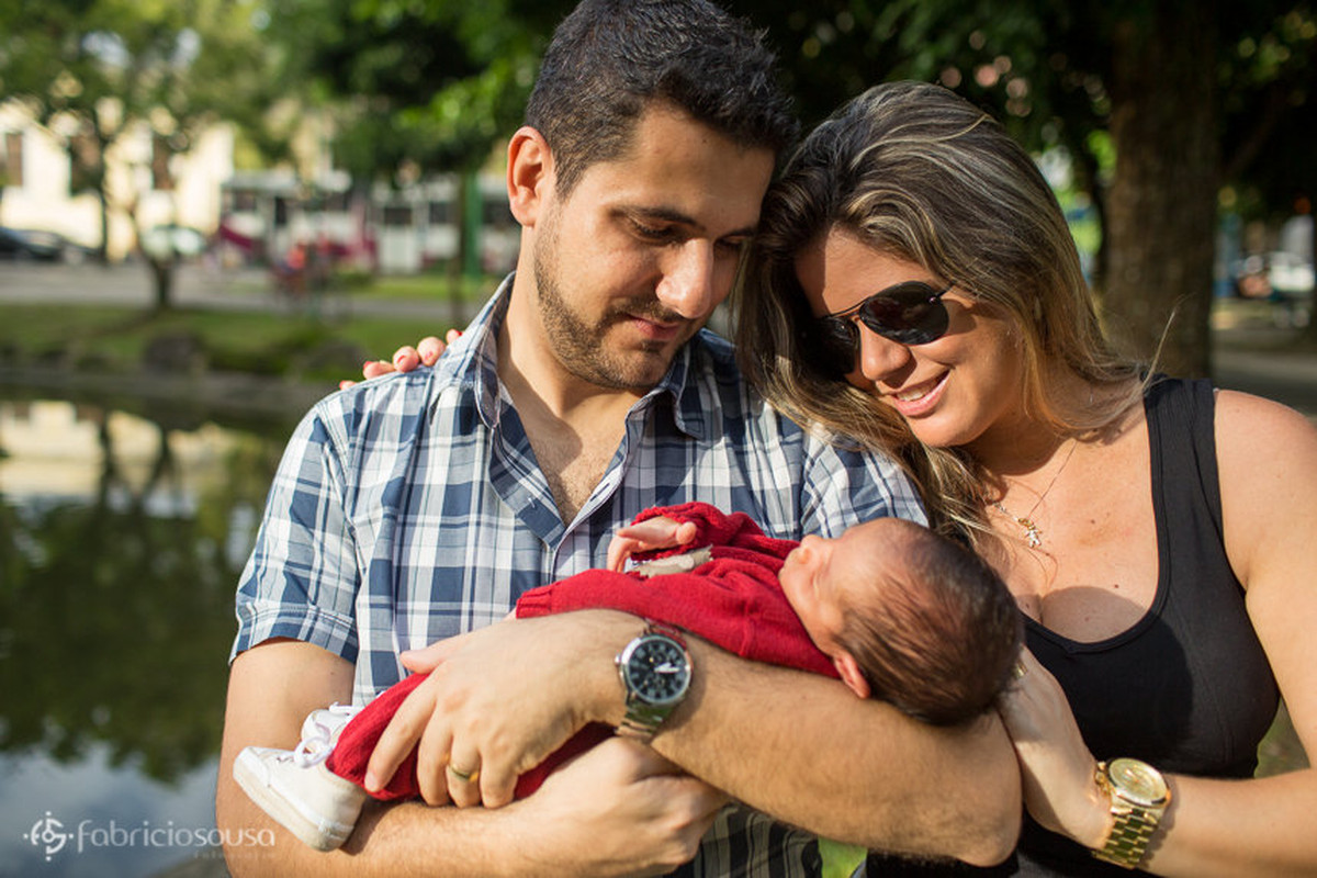 Paí segura Miguel e mãe ao lado aprecia o filho