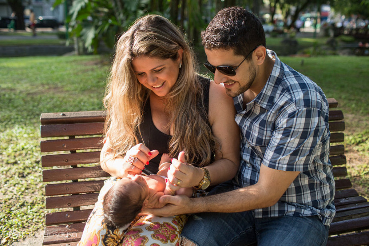 Dani e Leo sentados no banco da praça com o pequeno Miguel