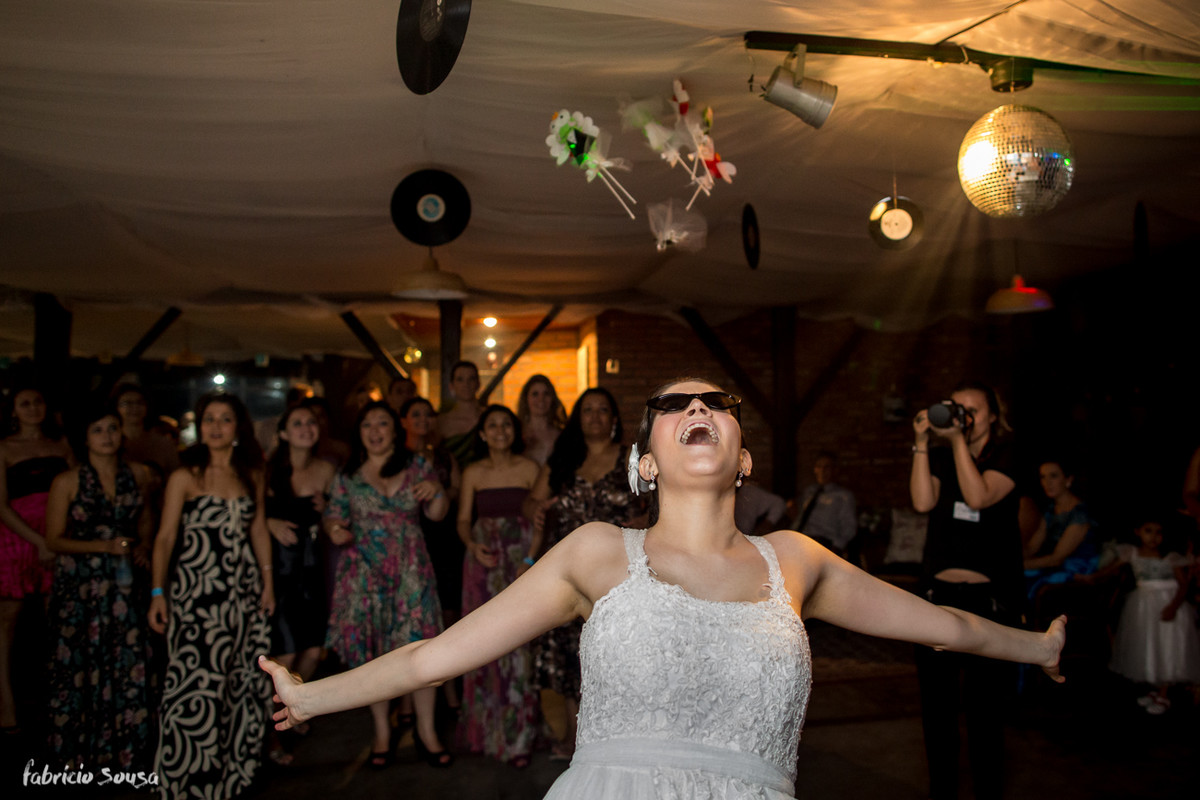 a noiva joga o buquet usando oculos escuros na festa