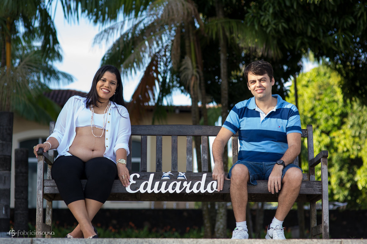 Mãe e pai seguram sentados a placa do nome do filho
