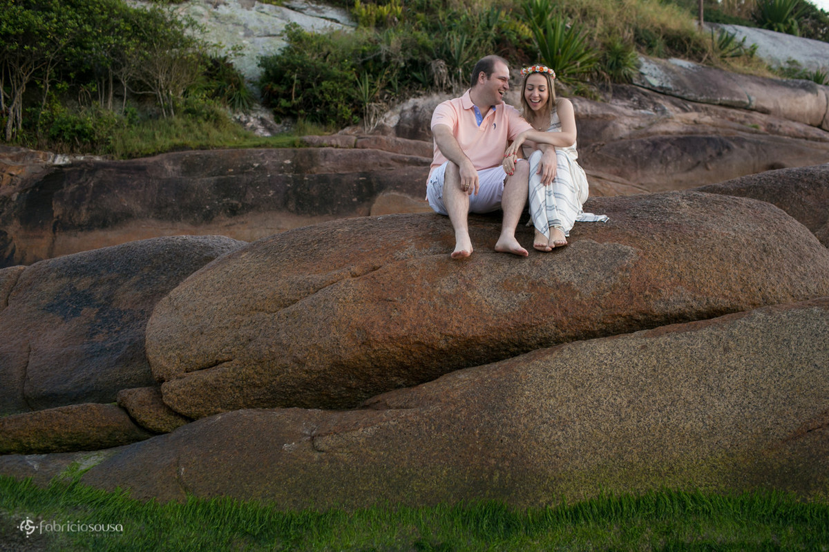 casal rindo em cima da pedra na praia da Barra da Lagoa