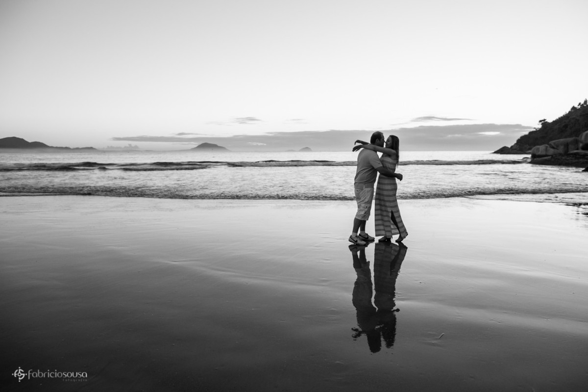 espelho d'água na areia da praia com casal se beijando