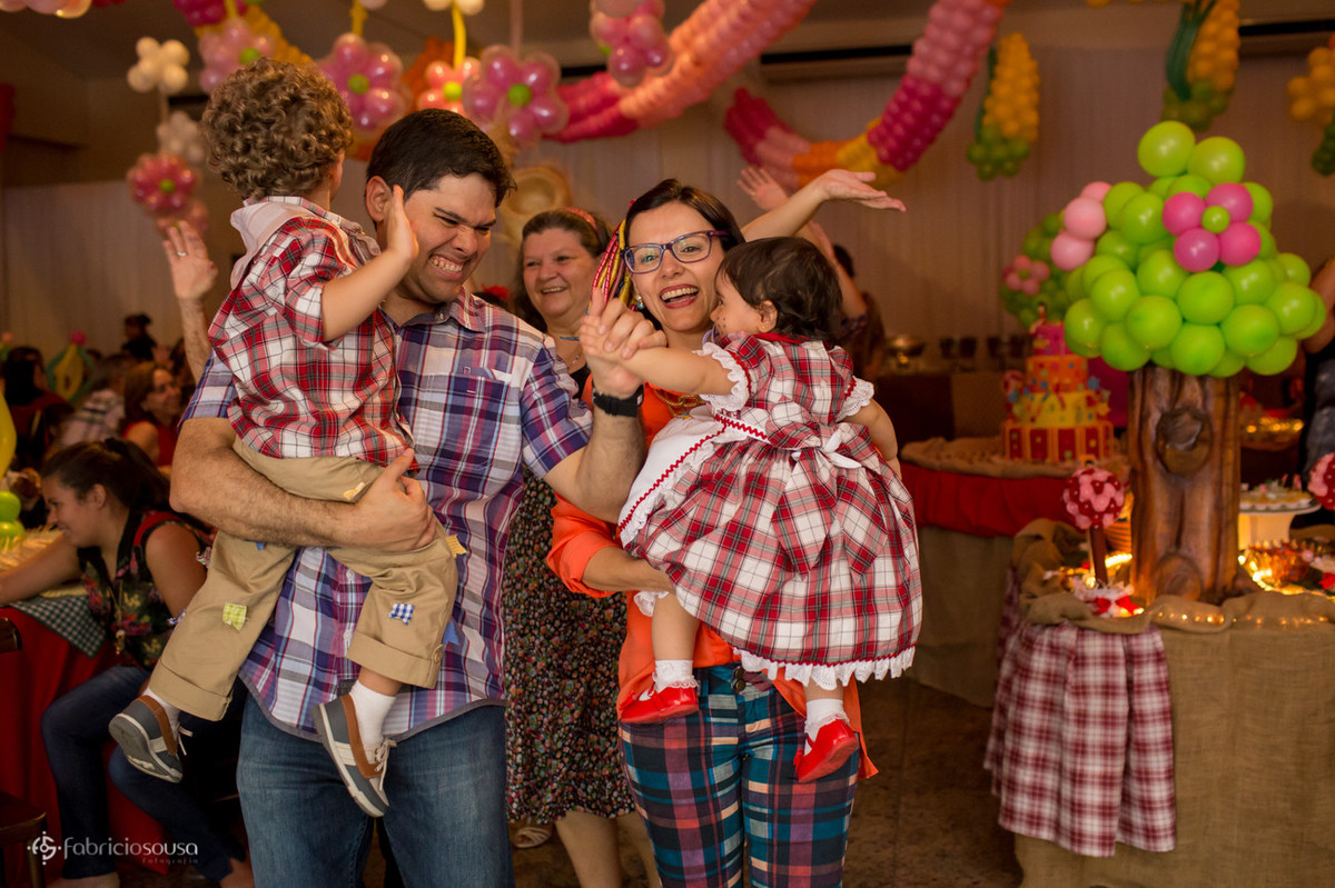 Beatriz no colo da mãe e vinicius no colo do pai agitando a festa