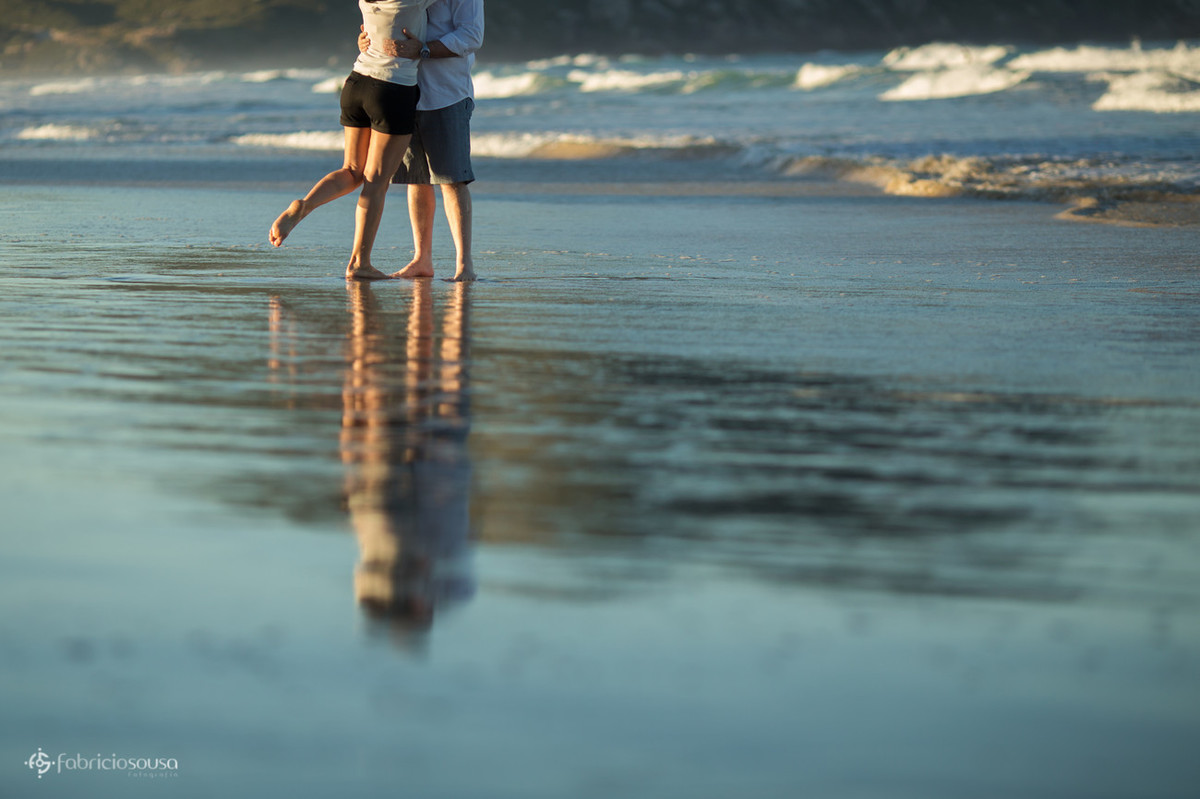 casal com o pé na areia da praia
