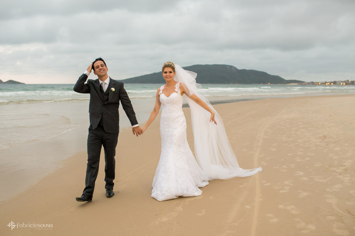 noivos caminham na areia da praia