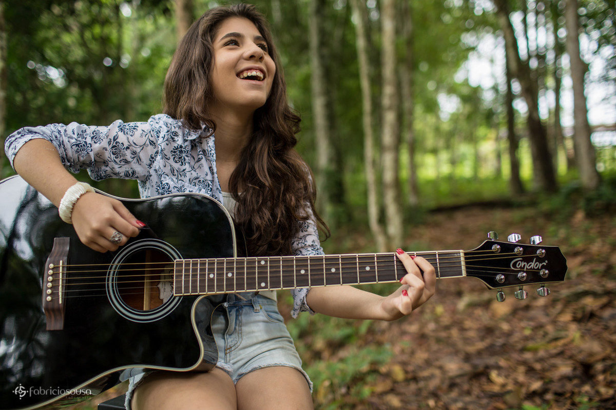Aniversariante tocando violão em meio à natureza do parque