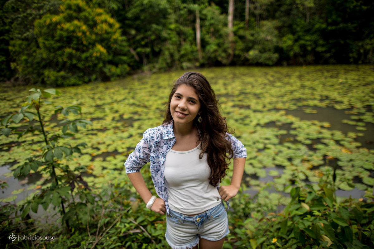 Juliana com as mãos na cintura em frente ao lago cheio de vitórias régias