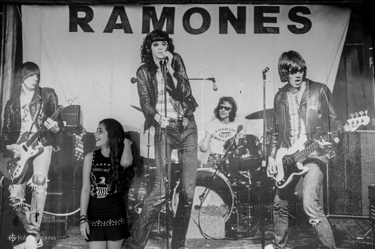 Ju posa na frente de uma grande imagem da banda Ramones