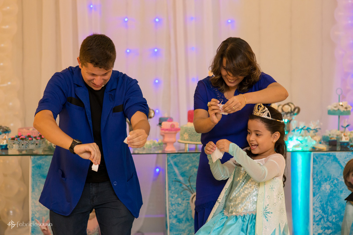 Mágico preparando truque com a aniversariante e mãe