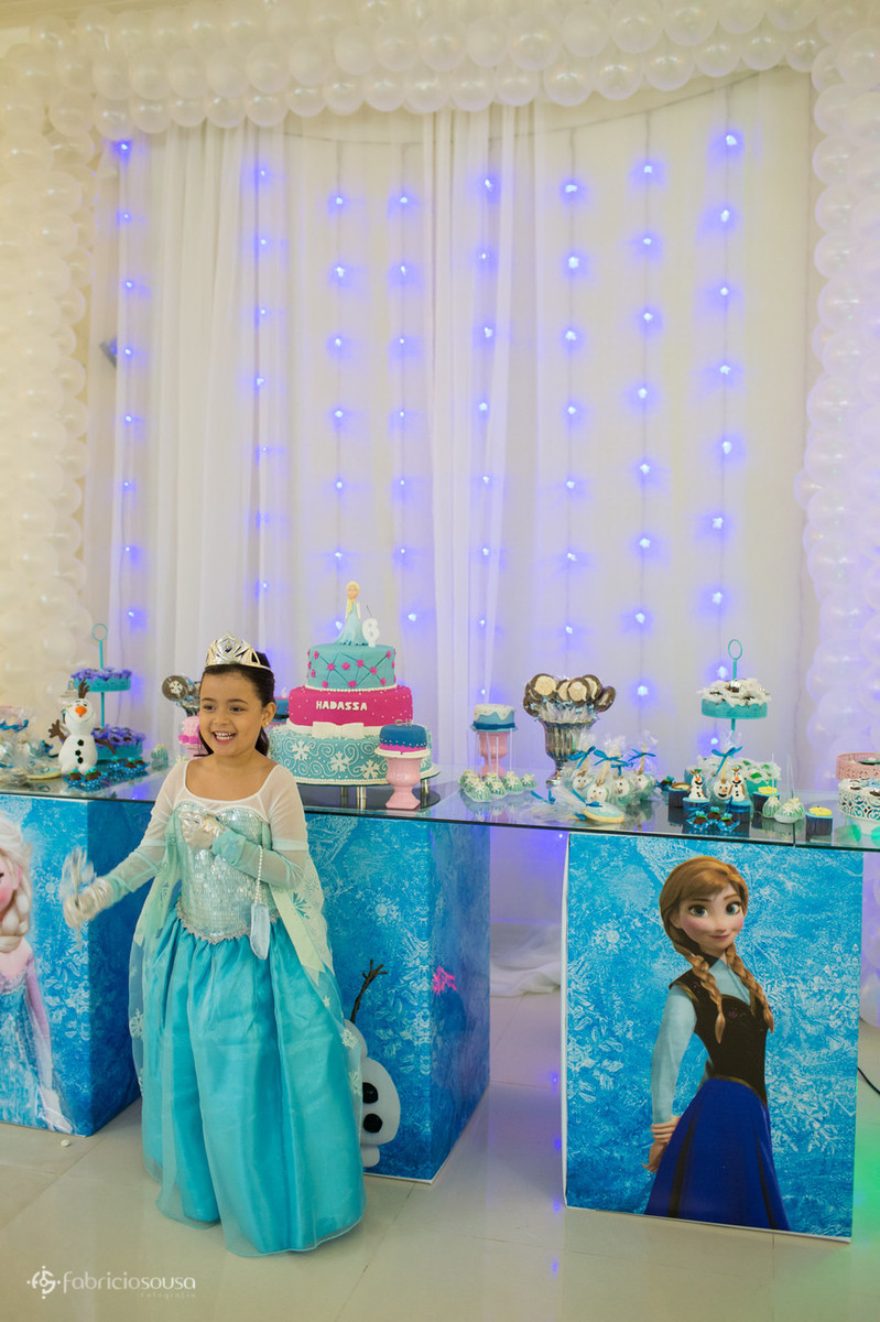 Posando em frente à mesa de doces com tema Frozen