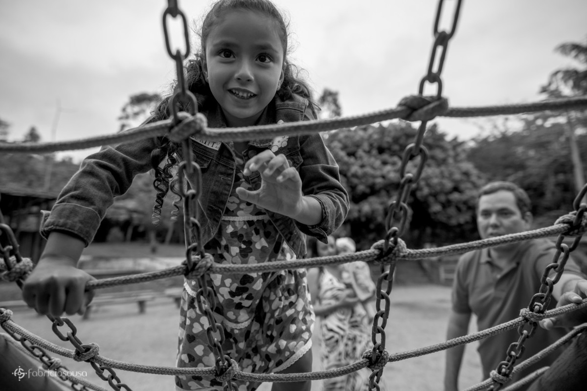 Laís brinca no parque enquantos seus pais a vigiam black and white