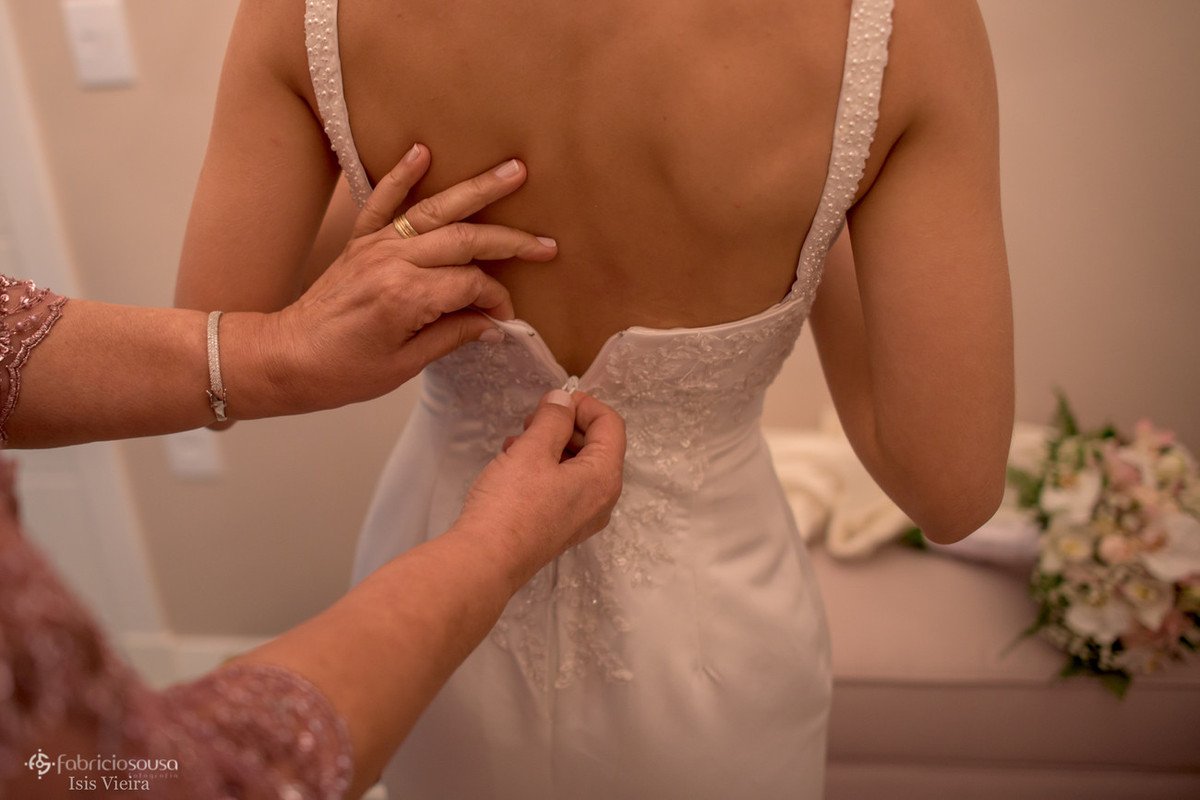 mãe fechando o vestido na noiva