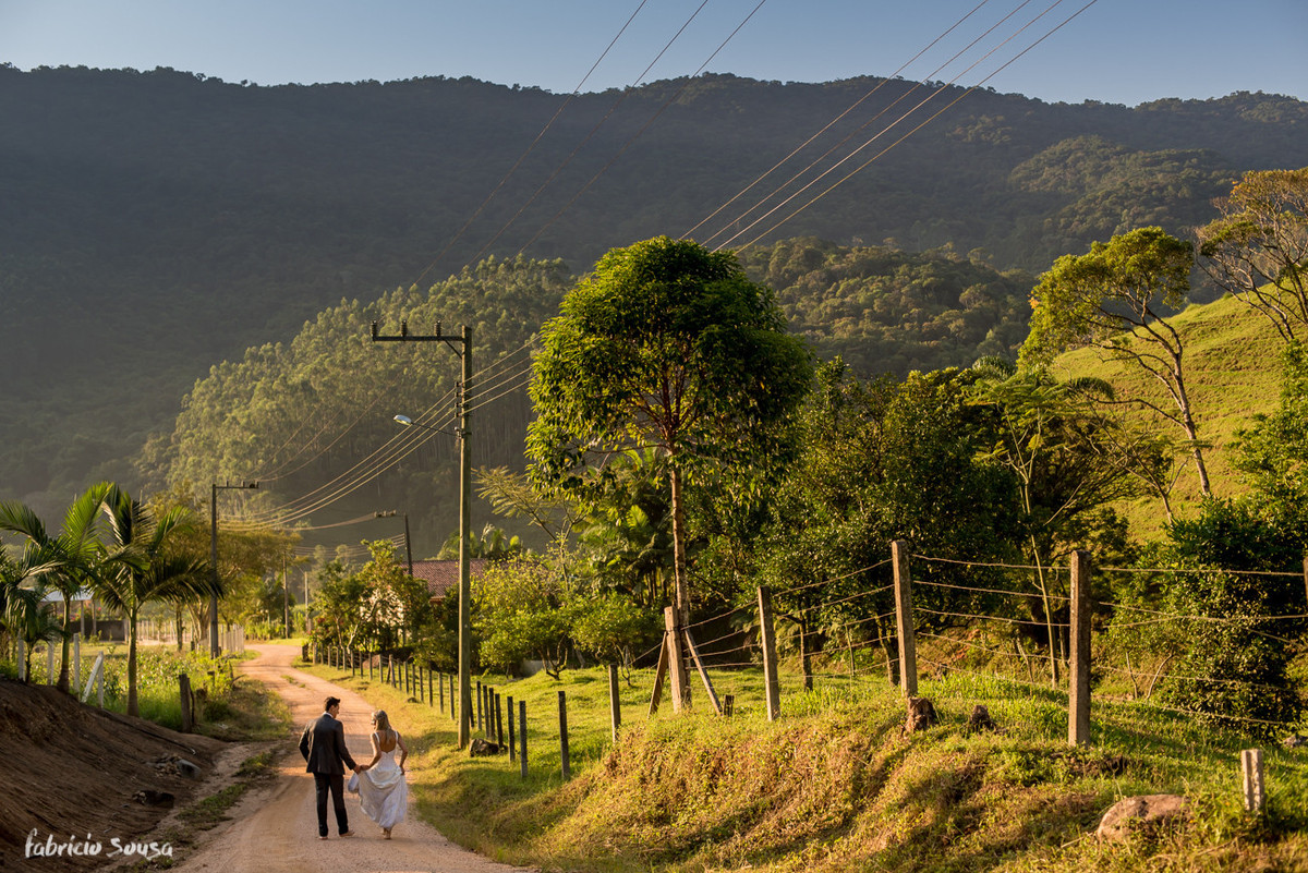 noivos caminham em estrada de chão em ensaio trash the dress