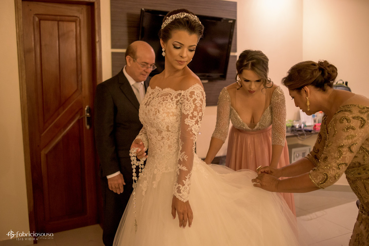 mãe e irmã ajudam a arrumar o vestido da noiva