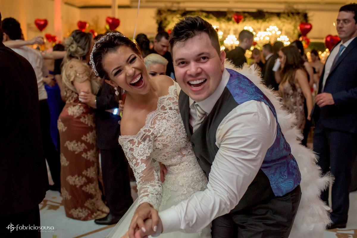 casal animado no final da festa. noivo de colete azul
