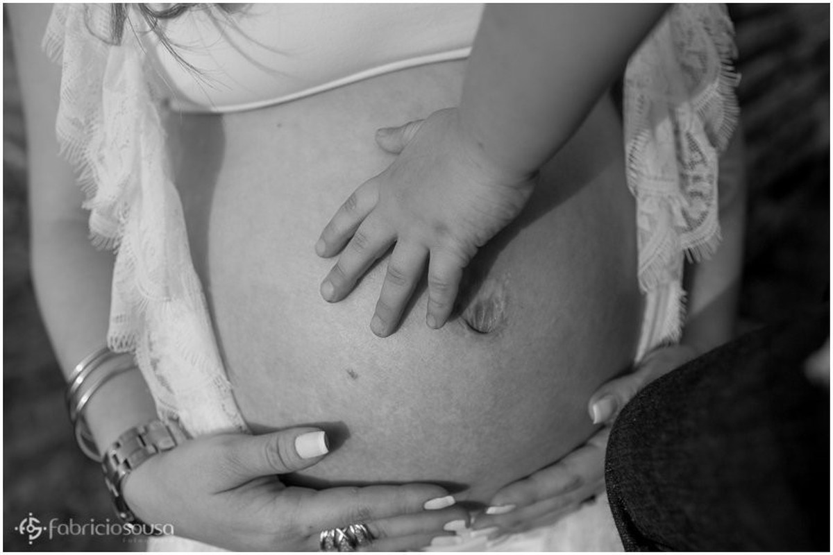 Close na barriga da mae com carinho da mão do irmão