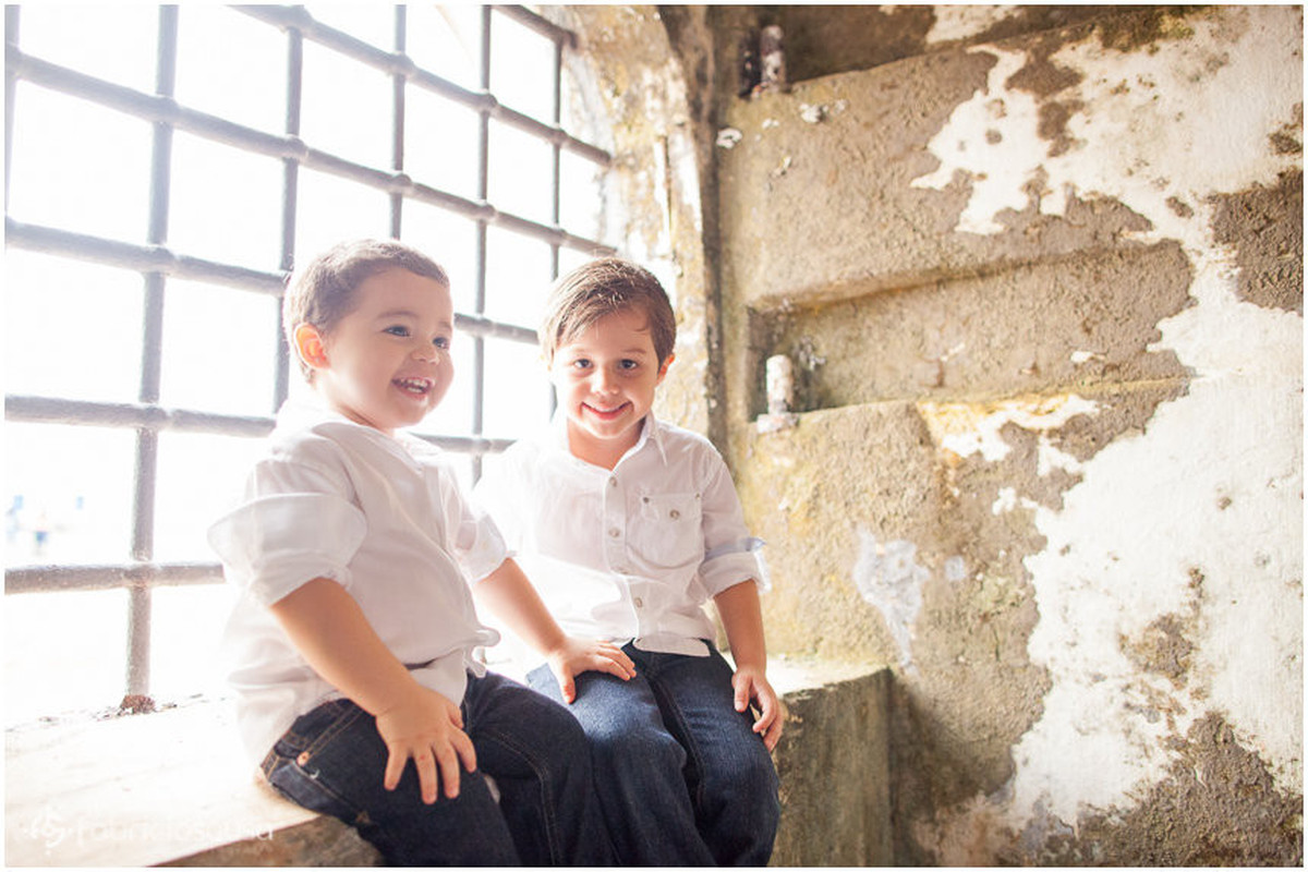 Meninos irmãos sorriem em frente à janela antiga