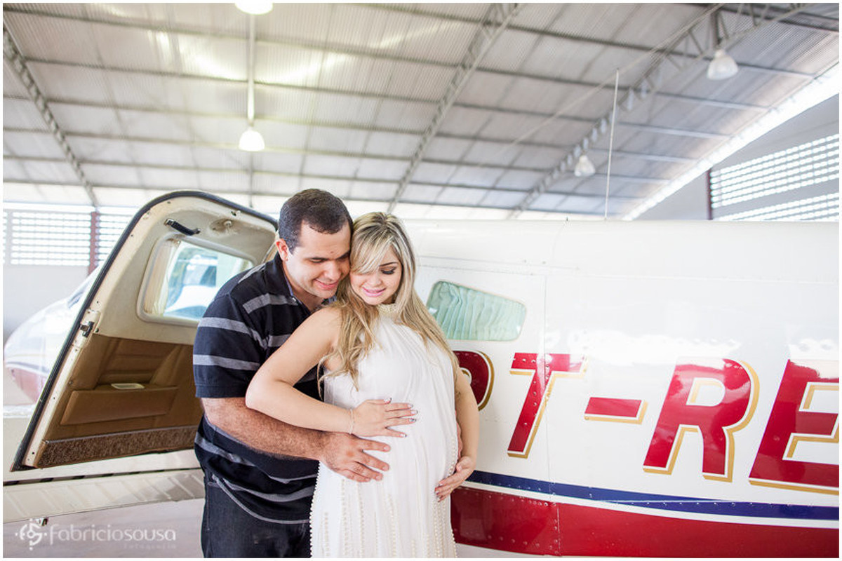 Casal envolve carinhosamente a barriga da mae no hangar