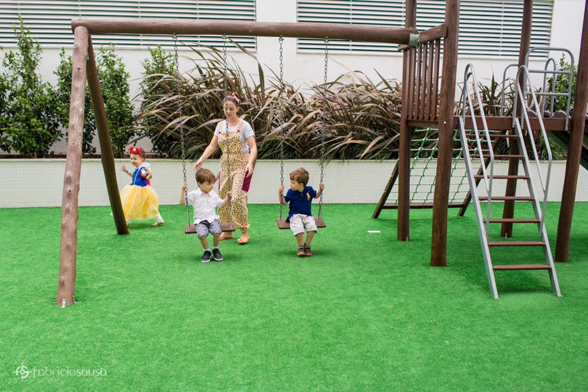 Crianças no balanço do parquinho infantil do prédio