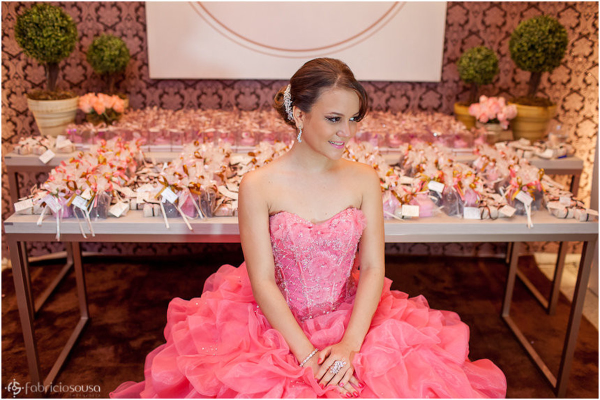 Debutante sentada em frente à mesa de doces