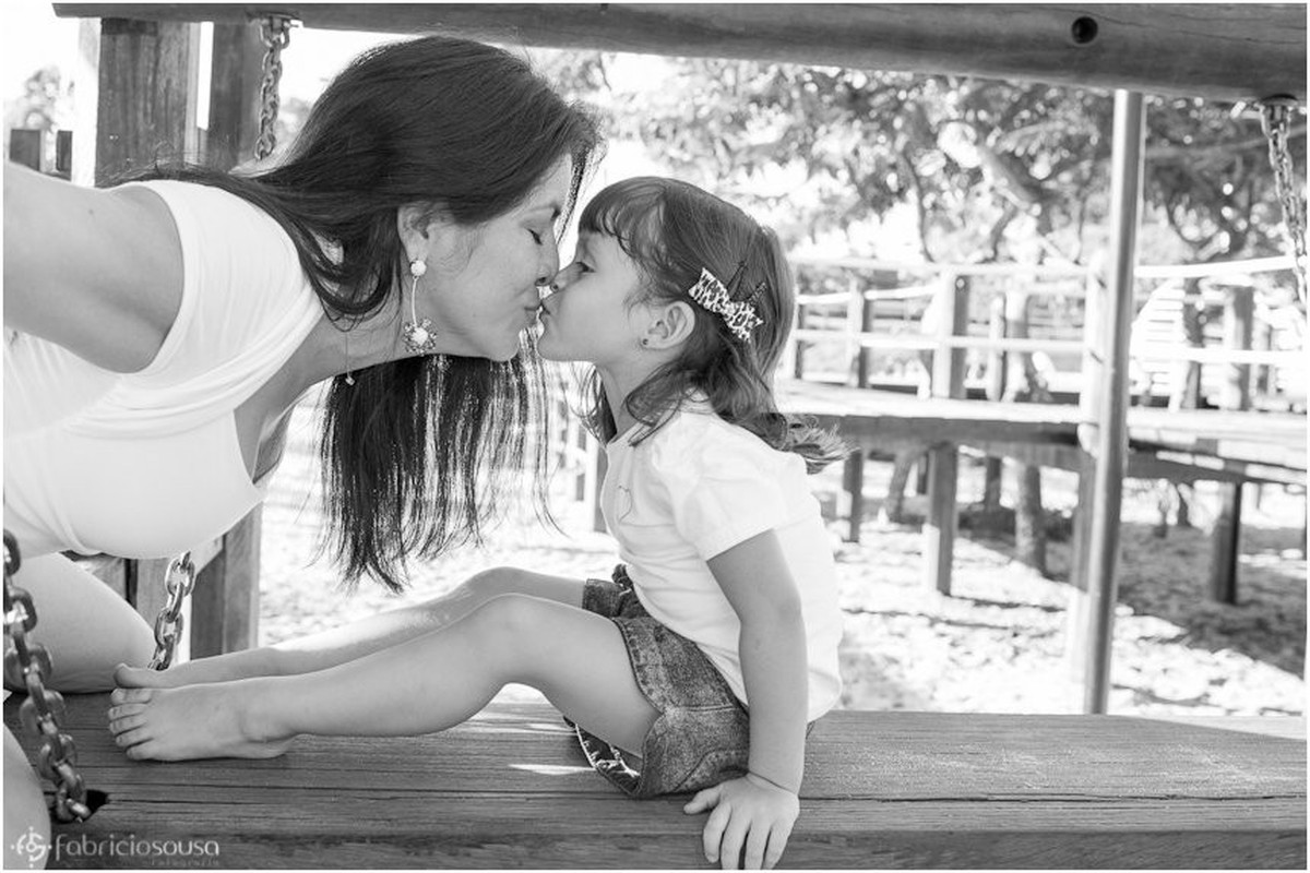 Mãe dá beijinho carinhoso na filha em ensaio fotográfico bw