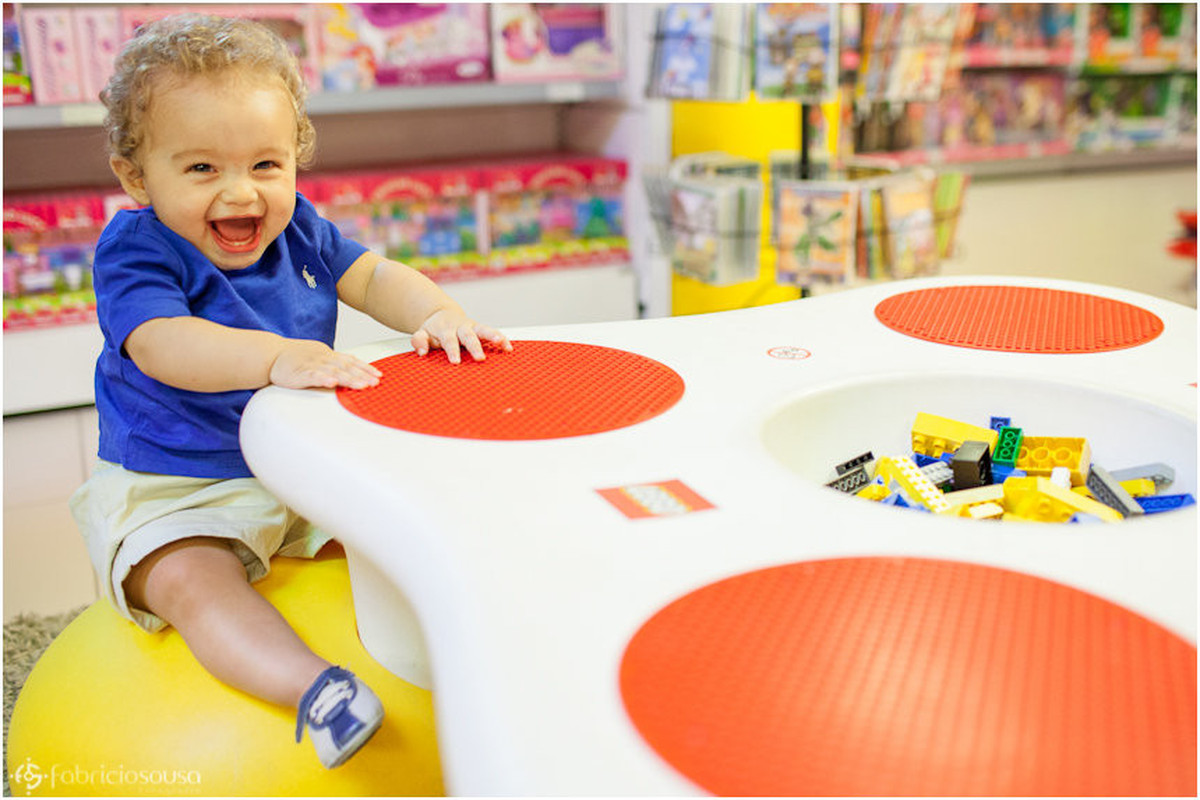 sessão infantil Vinícius sentando em mesa colorida