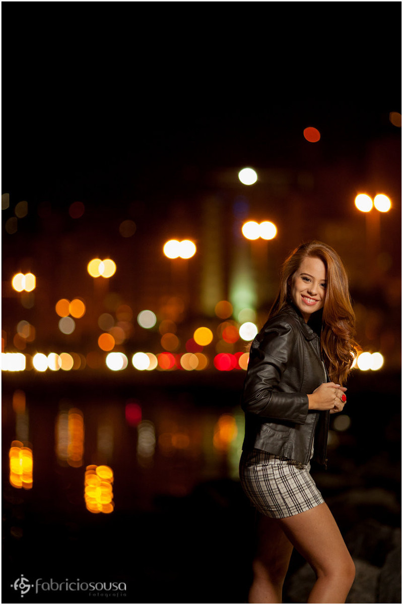 Nathalie sorridente com luzes da cidade ao fundo
