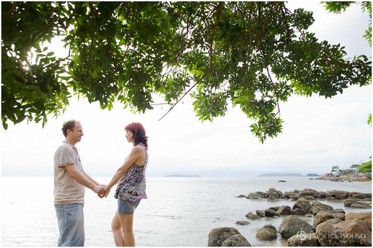 casal de mãos dadas com mar de Florianópolis de fundo