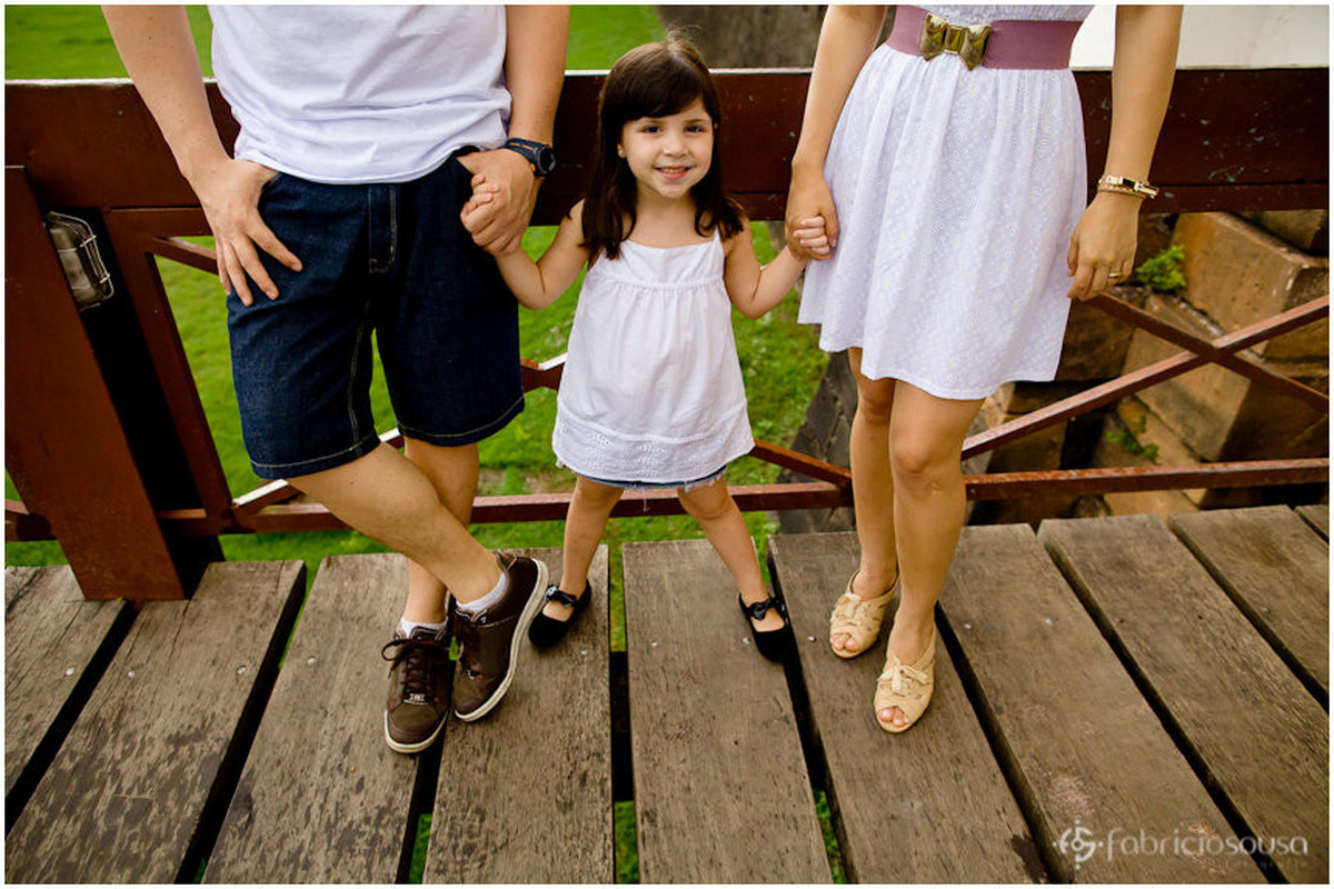 Menina de mãos dadas com os pais