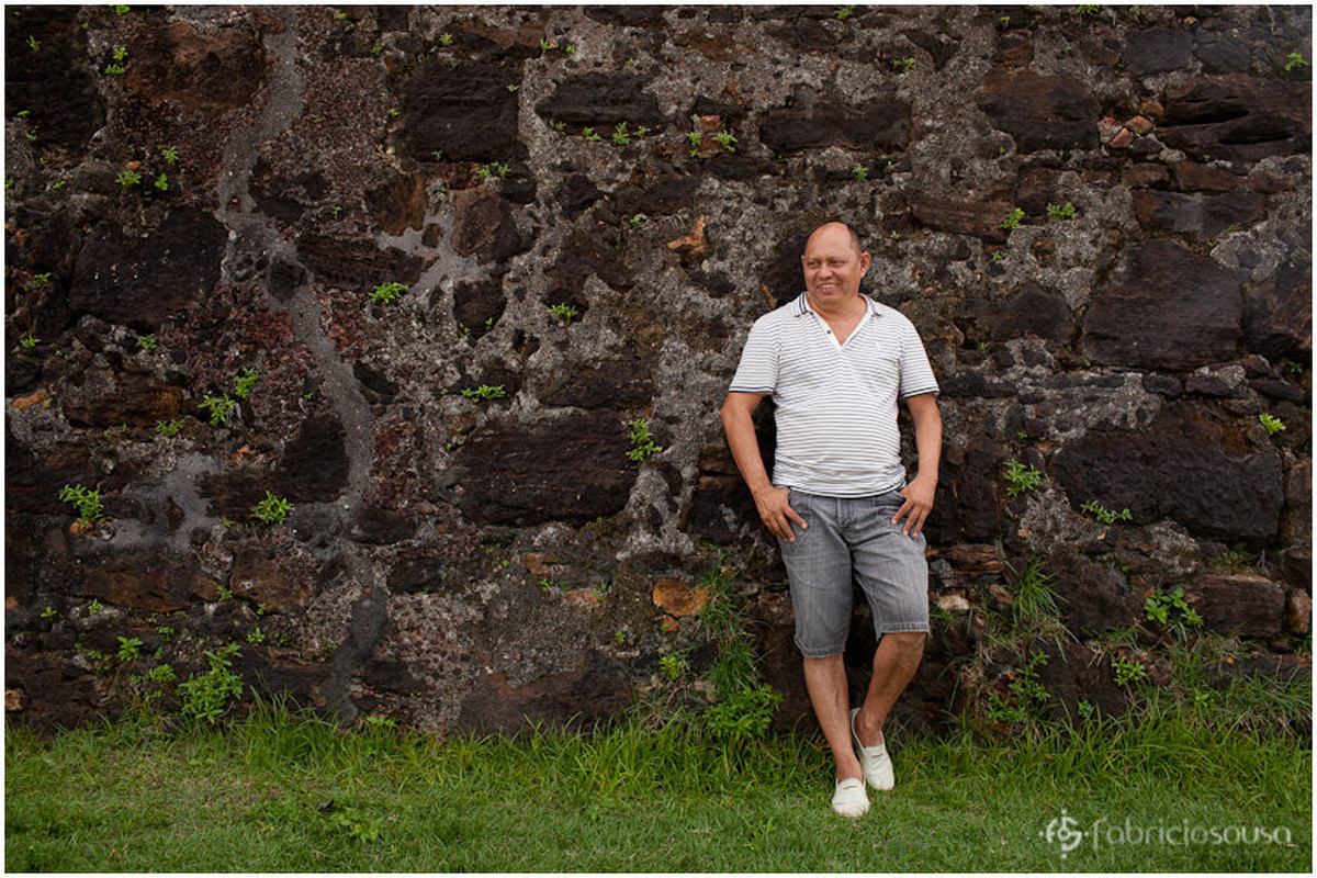 Pai de família escorado em muro de pedra
