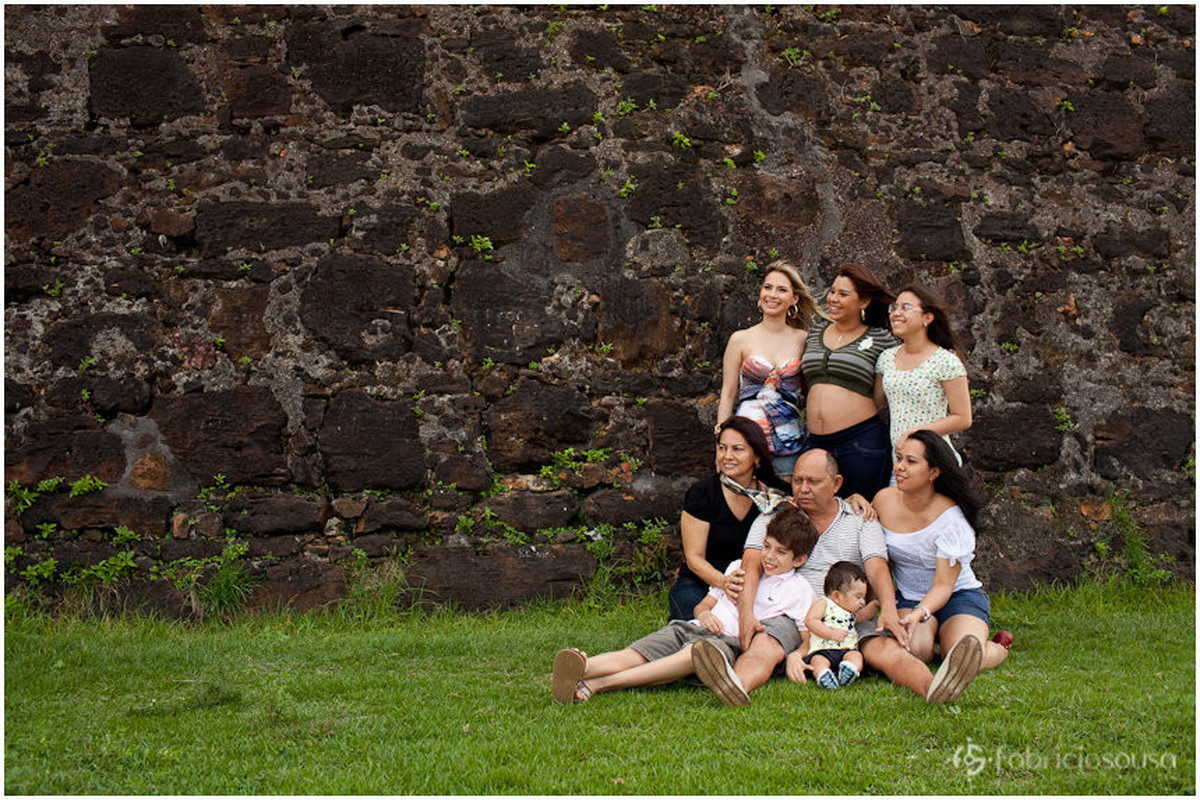 Retrato da família Almeida no gramado verde em frente ao muro de pedra