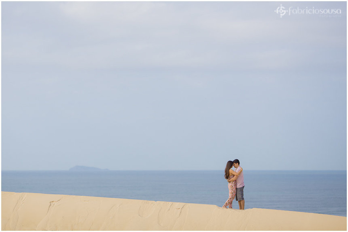 casal namorando nas dunas da joaquina. mar azul de fundo