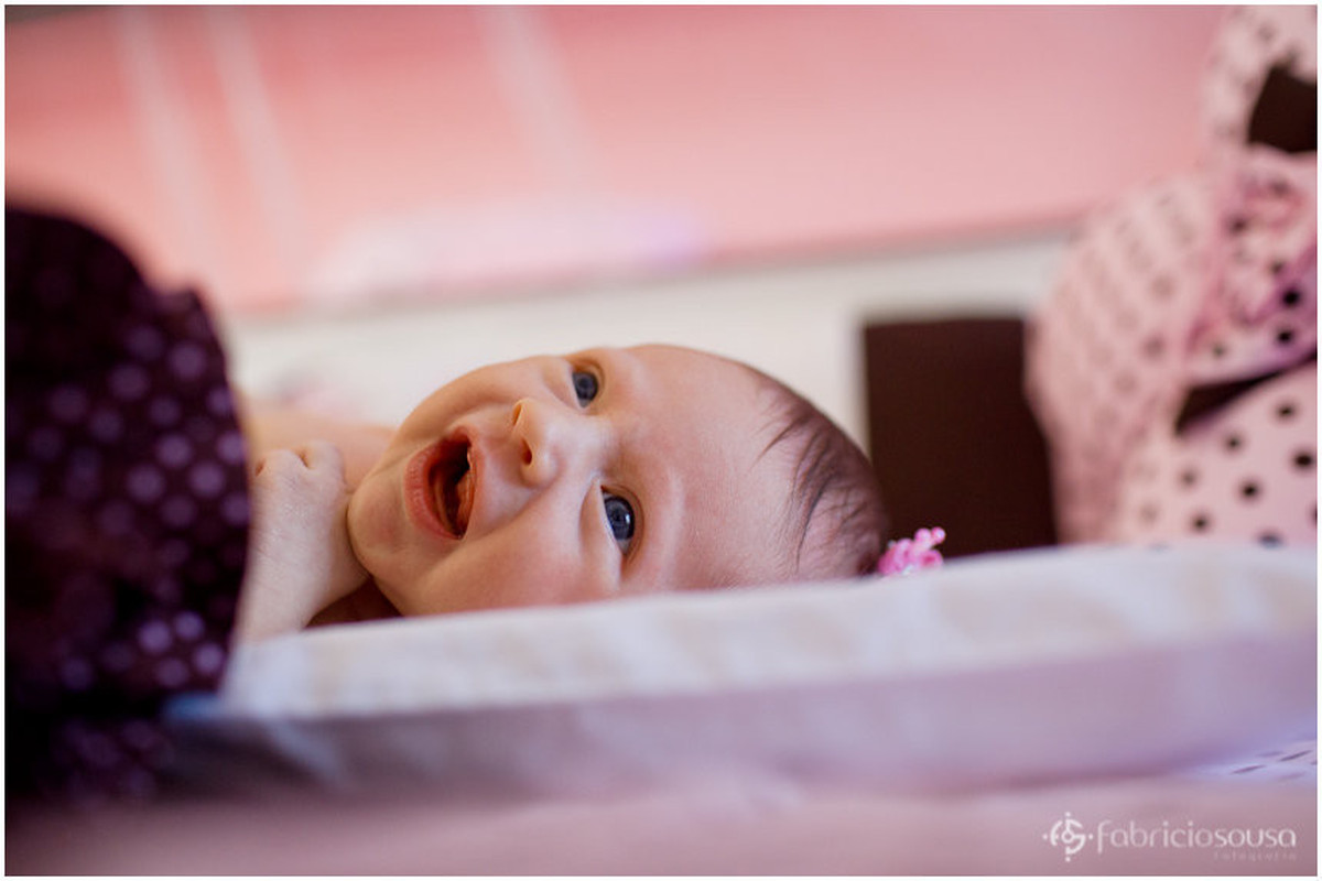 bebe sorrindo no berço cor de salmão e rosa